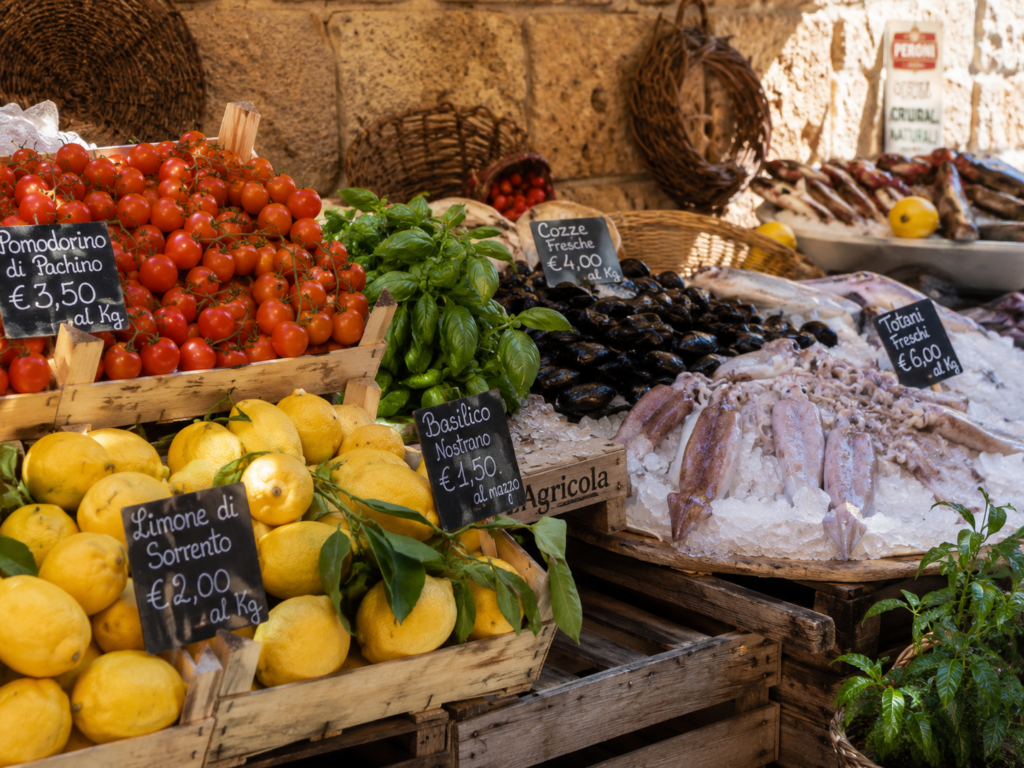 Summer market ingredients for panzanella di mare, including tomatoes, lemons, basil, and fresh seafood